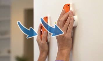 Pushing down on Hang Hero™ to attach nails to the wall